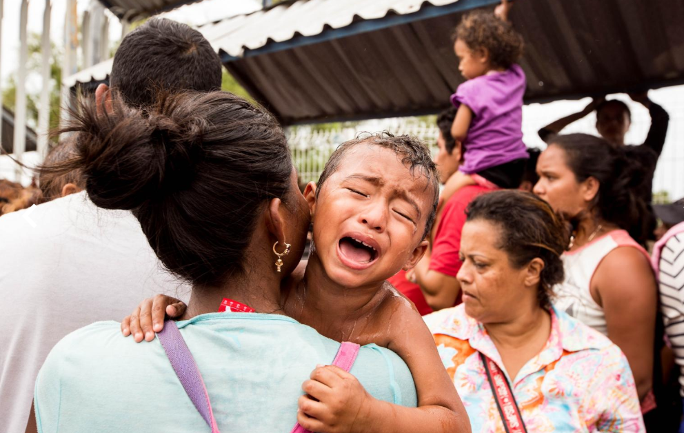 Viernes 19 de octubre. La mayor parte de la caravana de migrantes permaneció, al menos durante seis horas, bajo el intenso calor de la frontera de Tecún Umán, ante la imposibilidad de cruzar la frontera mexicana. En la fotografía, un niño, que se había desmayado sobre el hombro de su madre, recobra el conocimiento tras haber sido reanimado con un baño de agua fría (Fuente: Fred Ramos, El Faro).